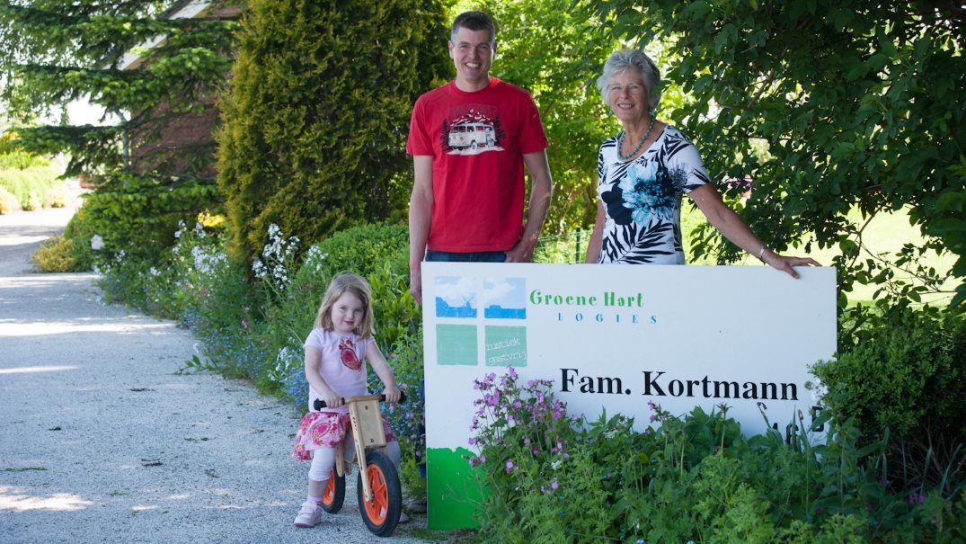 Familie Kortmann bij het welkomstbord van Kortmann Logies