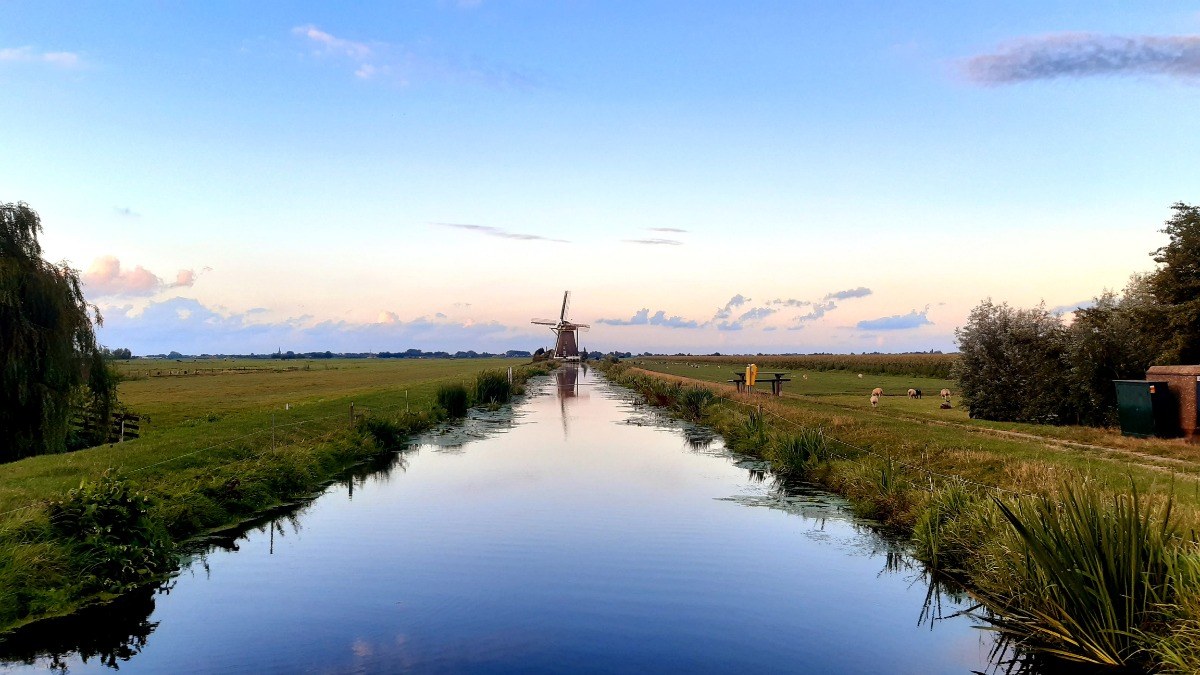 Molen aan de vaart in de polder bij zonsondergang