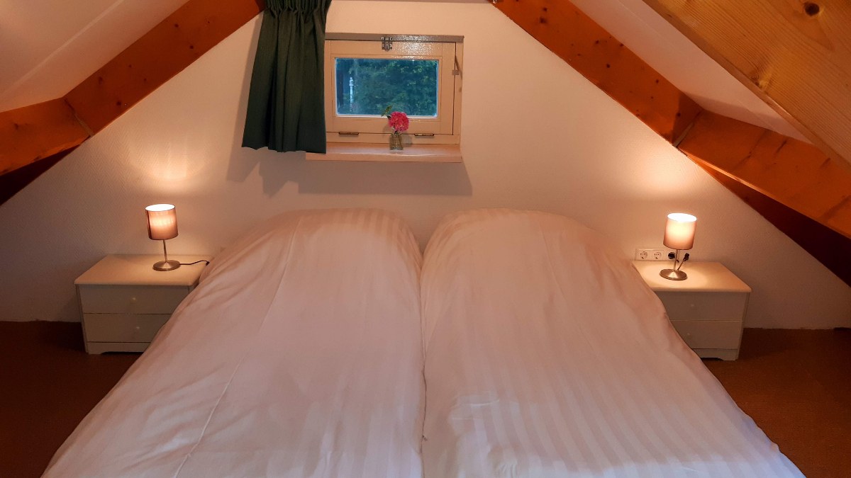Slaapkamer met tweepersoonsbed onder de dakkapel in Polderzicht