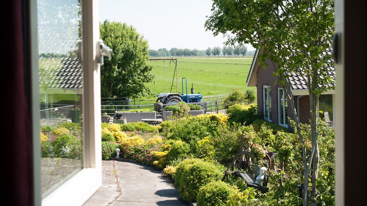 Uitzicht vanuit Weidezicht over de tuin richting de boerderij
