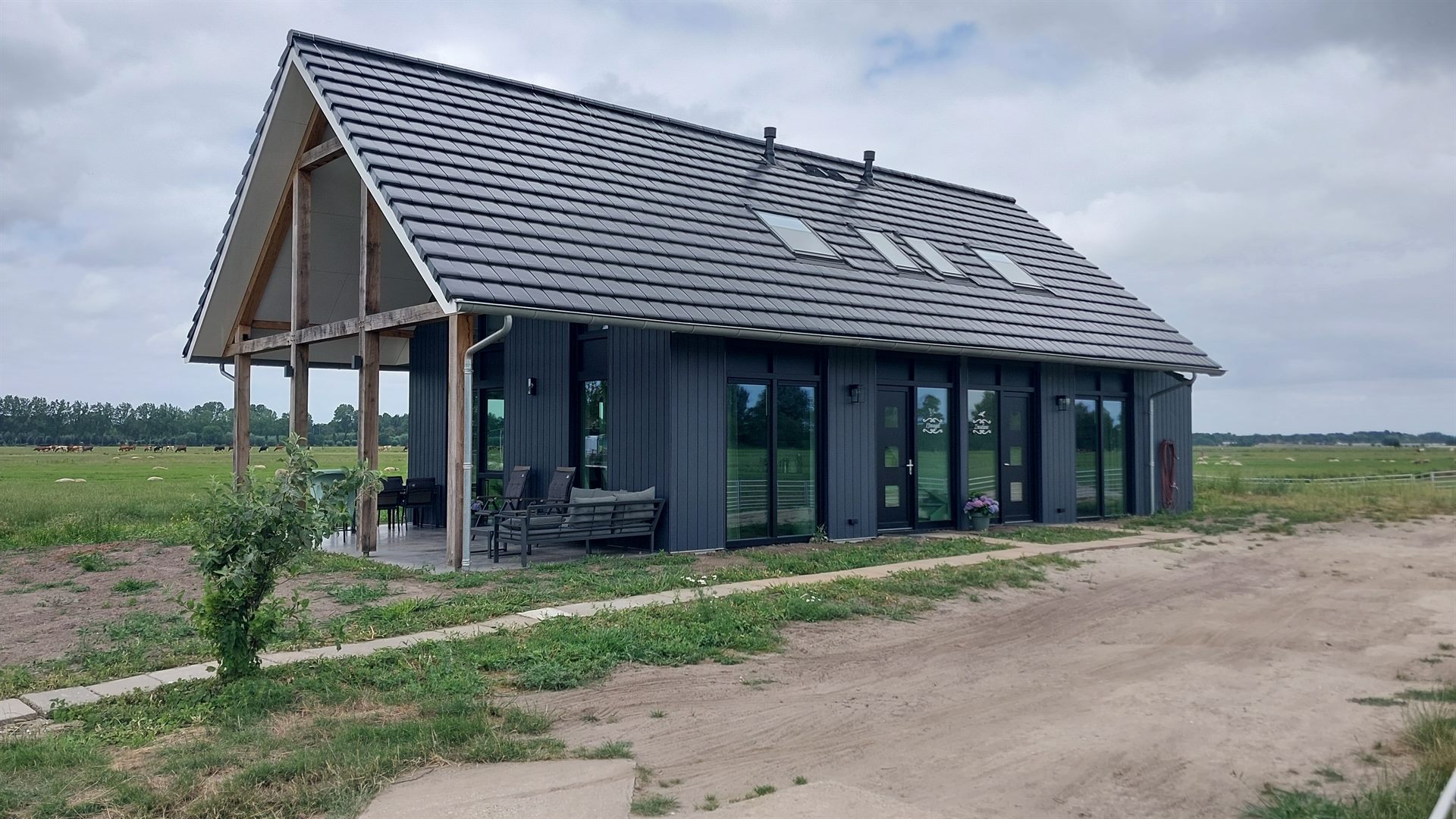 Vakantiewoningen Zwaluw en IJsvogel van buiten, met overdekte veranda en uitzicht op de polder